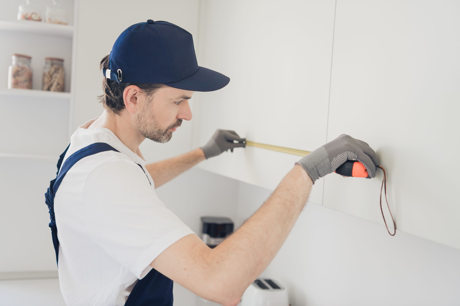 Professional handyman measuring kitchen cabinets during home renovation project with precise tools